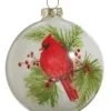 Ornement en forme de boule en verre. Cardinal sur une branche de pin.